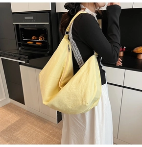 Detailansicht einer geräumigen gelben Nylon-Tasche in Halbmondform im Alltagskontext