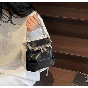Detail of black vintage kiss-lock bag with shiny oil wax leather and silver metal chain
