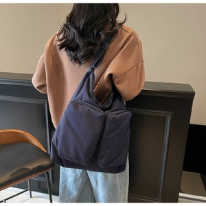 Detail of dark blue oversized crossbody bag with front pockets and adjustable strap