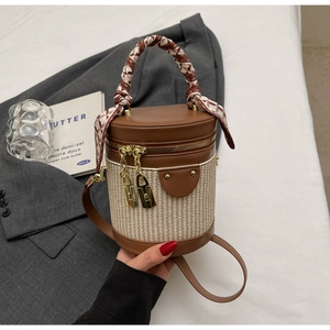 Detail of cylinder bag with brown leather, woven texture and silk scarf handle