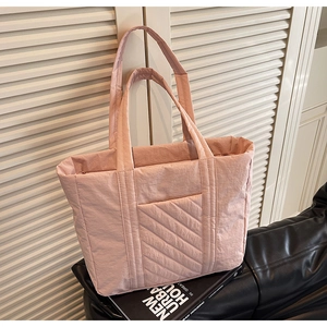 Detail of pink quilted tote bag showing padded nylon texture and front pocket