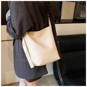 Close-up of minimalist beige bucket bag showing the premium lychee grain texture