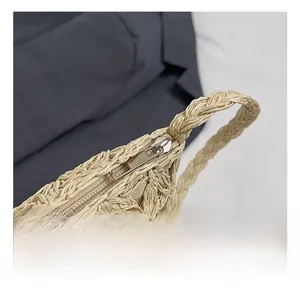 Nahaufnahme einer beigen Strohtasche mit silbernem Reißverschluss und geflochtenem Griff
