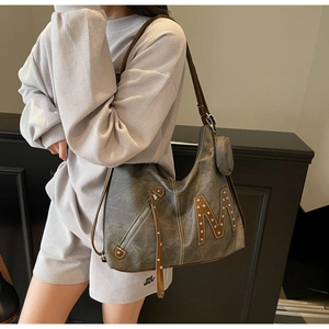 Detail of vintage tote bag showing brown M patch, silver rivets and tassel zip details