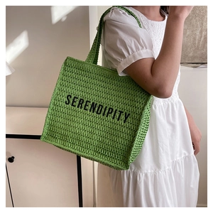 Close-up of green woven tote bag featuring black SERENDIPITY printed lettering