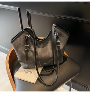 Detail of black leather tote bag with silver buckles and embossed WWTC lettering