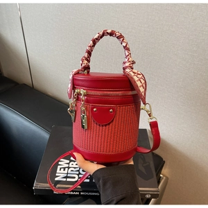 Detail of red cylindrical bucket bag with silk scarf handle and braided texture