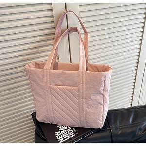 Detailed close-up of pink quilted nylon tote bag with double handles on a black stand