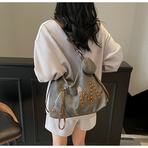 Detail view of large tote bag in grey canvas with brown leather M patch and mini pouch