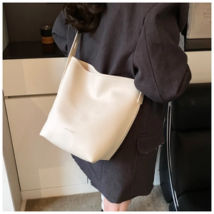 Detail of off-white leather bucket bag showing grain texture and brand logo