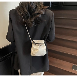 Chic cream mini chain crossbody bag with silver clasp shown on a model on stairs