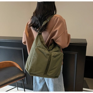 Detail of dark green canvas bag showing dual front utility pockets and wide strap