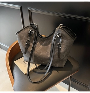 Detail of grey canvas tote bag with black leather trim and silver metal buckles