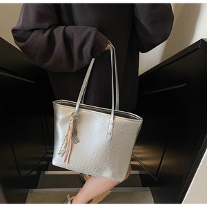 Detailed macro view of a silver tote bag with metallic texture and woven rope charm