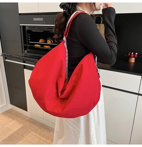 Detail der roten sichelförmigen Segeltuchtasche an Model in minimalistischer Küche