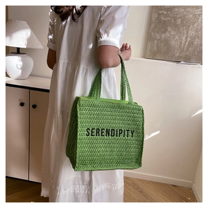 Close-up of green knit tote bag with black Serendipity text and thick braided handles