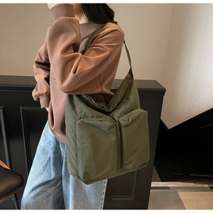 Detail of olive green nylon tote bag featuring functional large front cargo pockets