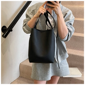 Detailed view of black pebbled leather bucket bag with adjustable strap and logo