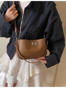 Brown leather underarm bag with silver buckle and adjustable strap worn by a model