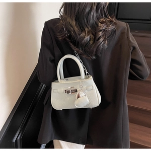 Sage green mini bucket bag with silver chain strap shown in a staircase lifestyle setting