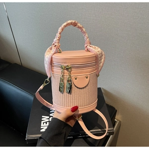 Detail of pink cylindrical bucket bag with woven leather texture and silk scarf handle