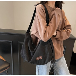 Detail of black corduroy hobo bag with adjustable strap and vintage brand patch
