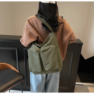 Olive green canvas shoulder bag detail featuring two front cargo pockets and wide strap