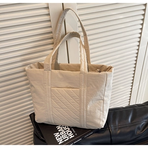 Detailed macro view of beige quilted nylon puffer tote bag showing soft puffy texture