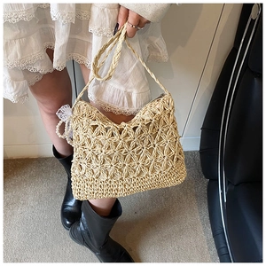 Detail der Strohtasche mit hohlen Blumenmustern und dekorativem Perlenspitzenanhänger