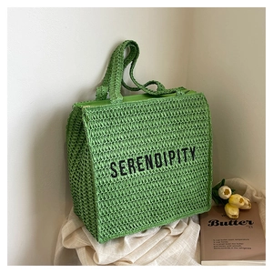 Close-up of green woven tote bag with Serendipity text and stylish tulip decor