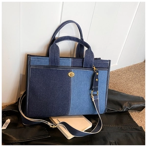 Gros plan du sac fourre-tout en denim bicolore avec fermoir doré sur une veste en cuir
