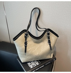 Close-up of matte grey tote bag with black leather straps and silver metal buckles