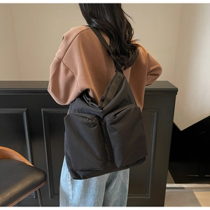 Detail of a black nylon crossbody bag with dual utility pockets shown on a model