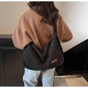 Model wearing a large black corduroy crossbody bag showing high capacity and soft drape
