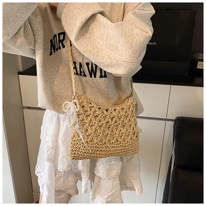 Detail der gewebten Strohtasche mit Perlen-Schleife und zarten Spitzenbändern