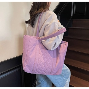 Detail of the purple quilted tote bag showing texture and reinforced wide shoulder strap