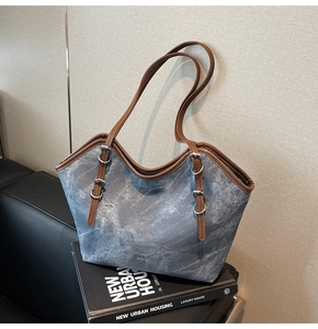 Close-up of blue washed denim texture with brown leather straps and metal buckle details