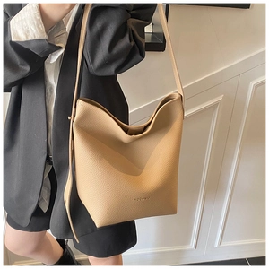 Close-up of khaki bucket bag with lychee grain leather texture and brand logo detail