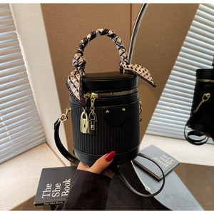 Detail of black woven cylinder bag with decorative silk scarf and gold zippers