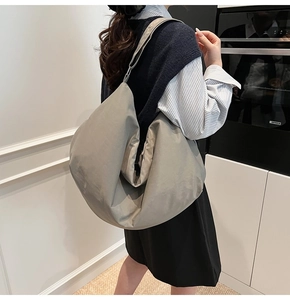 Detailansicht der grauen Hobo-Tasche mit weichem Stoff und breitem Schultergurt für Damen