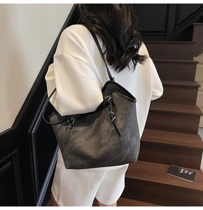 Detail of charcoal grey tote bag showing matte texture and WWTU logo in a staircase setting