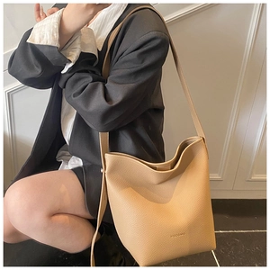 Detail of khaki pebbled leather bucket bag featuring elegant brand lettering and strap