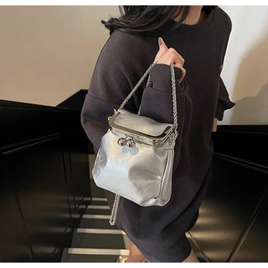 Detail of silver vintage kiss-lock bag with metallic chain on a model in a stairwell