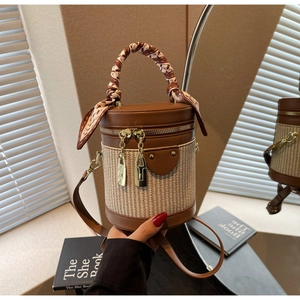 Detail of woven cylinder bag featuring brown leather trim and decorative silk scarf
