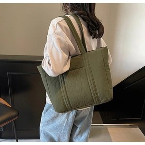 Detailed close-up of olive green quilted tote bag with soft texture and shoulder straps