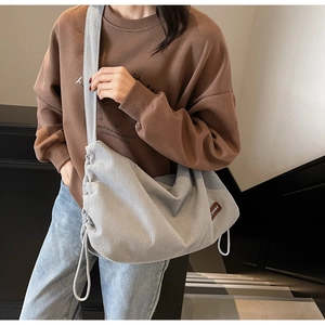 Detail of light blue corduroy shoulder bag with side drawstring and brand leather tag