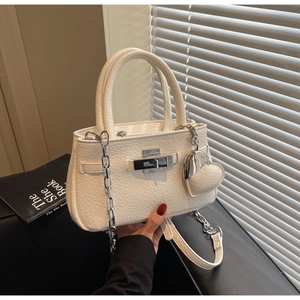 Detail of white lychee leather texture with silver clasp and heart charm on bucket bag
