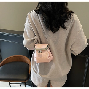 Detail of pink vintage clasp crossbody bag with silver chain strap on model back