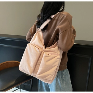 Rear view of large pink canvas tote bag with dual front zipper pockets on model