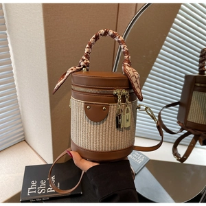 Detail of vintage cylinder bag with woven texture, leather trim, and scarf-wrapped handle